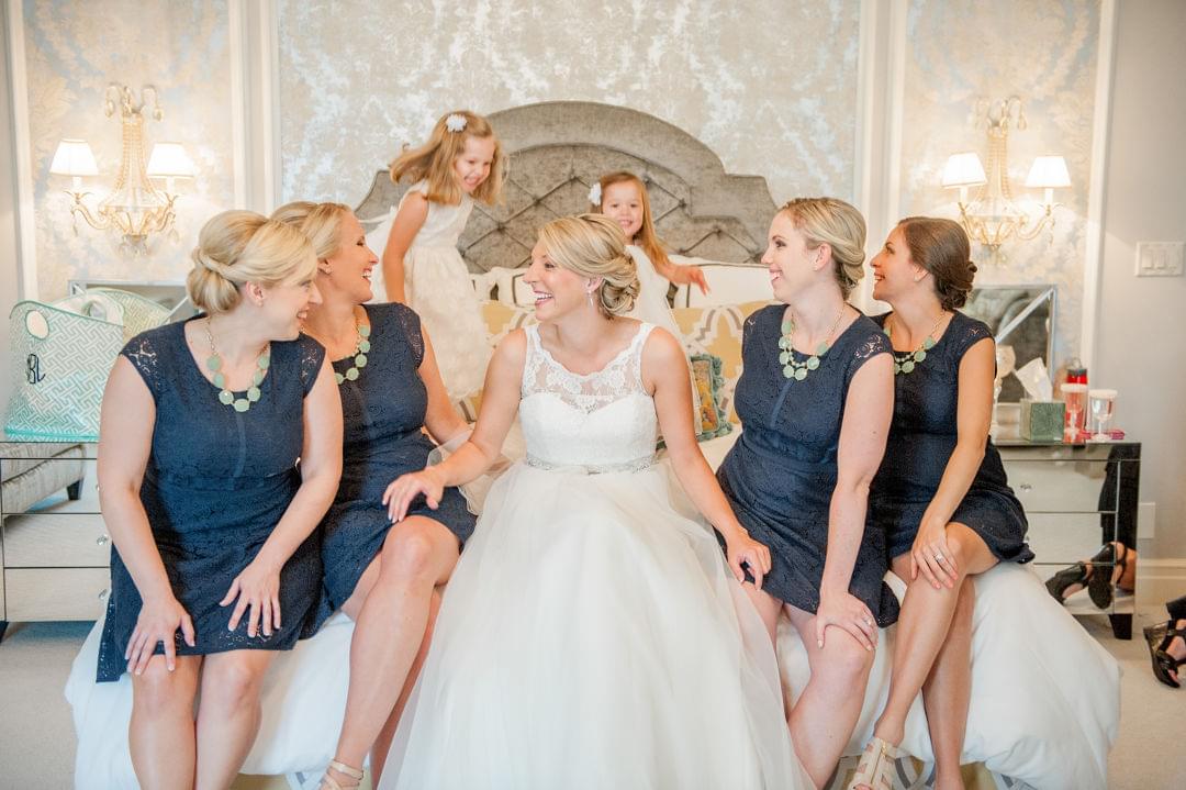 Kelsey sits on bed with her bridal party