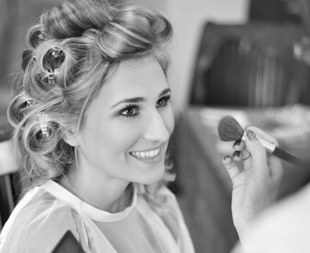happy bride getting hair and makeup professionally done
